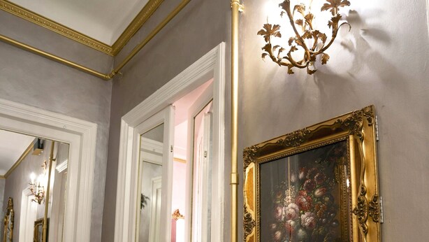 A hallway with a mirror, a chandelier, and a framed artwork on the wall. - VACATIONS IN THE HEART OF ROME COLOSSEUM (Roma)