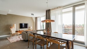 A modern living room with a dining area, large windows, a flat-screen TV, and a view of the city. - Apartment in Zeeheldenkwartier (The Hague)