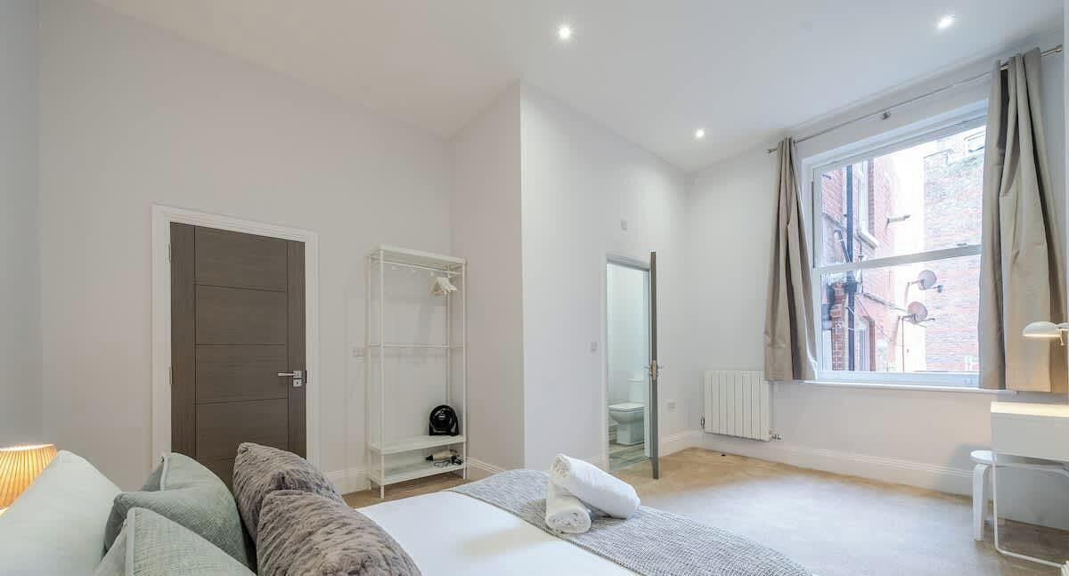 Een slaapkamer met een bed, een kledingkast, een radiator, een raam en een deur.