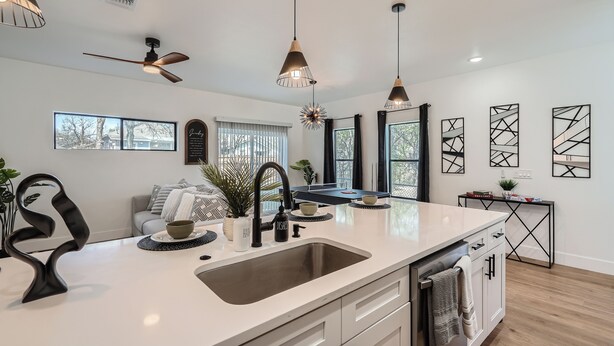 A modern kitchen with a central island, pendant lights, and a ceiling fan.