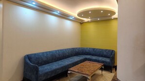 A modern lobby with a blue sofa, a small wooden table, and a yellow accent wall. - The waypointinn (Shimla)