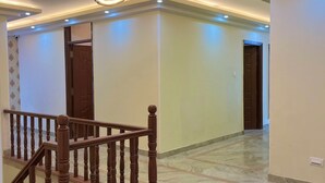 A spacious hallway with a marble floor, a wooden staircase with a balustrade, and recessed lighting. - The waypointinn (Shimla)