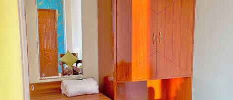 A room with a wooden wardrobe, a bench with a towel, and a patterned rug.