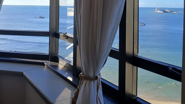 Une pièce dotée d’une grande fenêtre donnant sur la mer et sur un navire au loin.