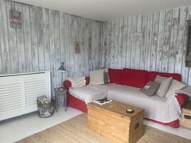 A cozy living room with a red sofa, a wooden chest, and a radiator.