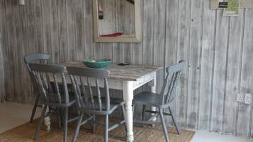 A dining area with a wooden wall, a table, four chairs, and a mirror.