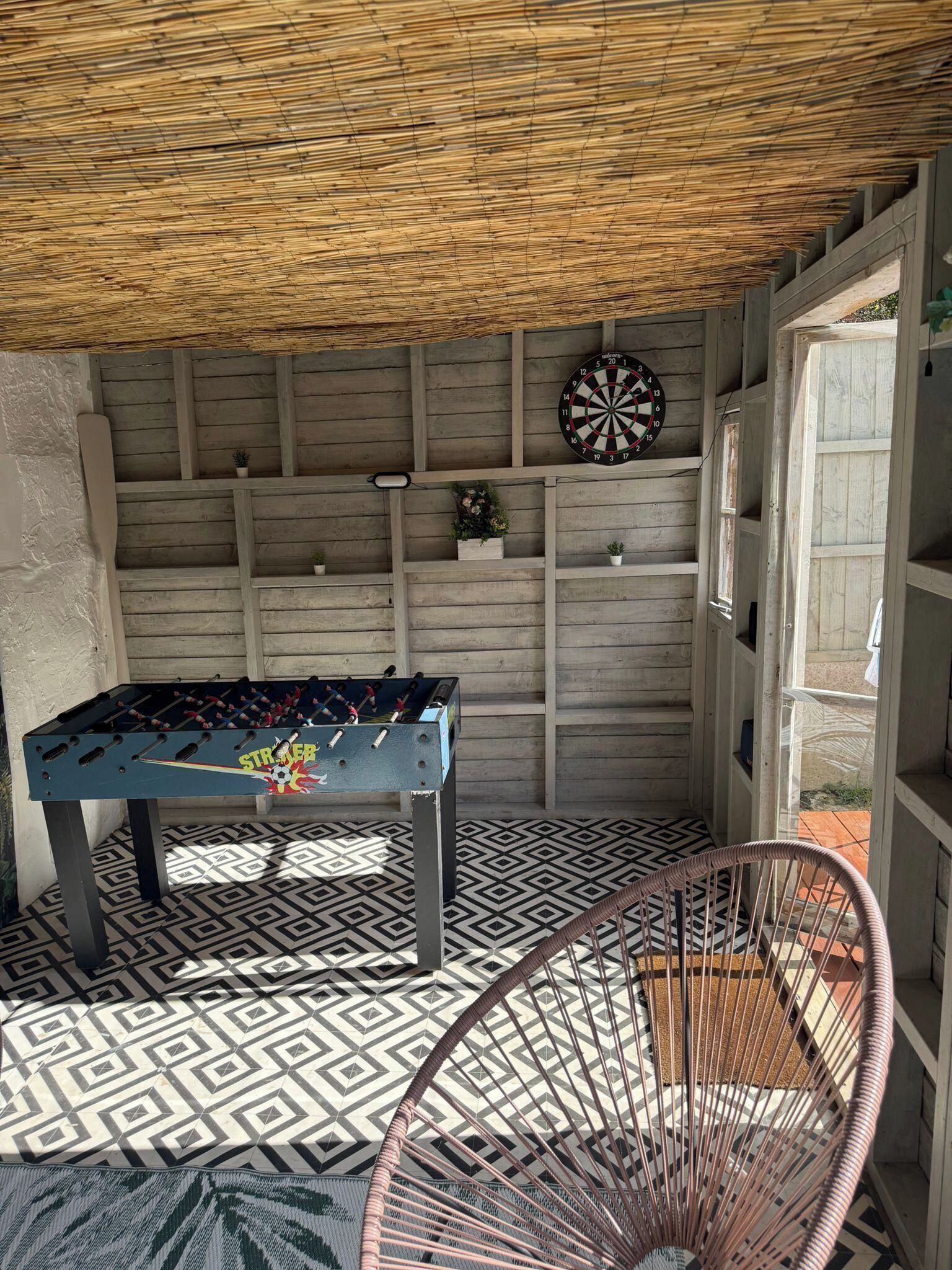Um quarto com mesa de pebolim, dardos e uma cadeira.