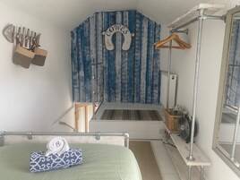 A bedroom with a bed, a hanging shower, and a radiator.