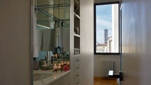 A bathroom with a large mirror, a bathtub, and a window with a city view.