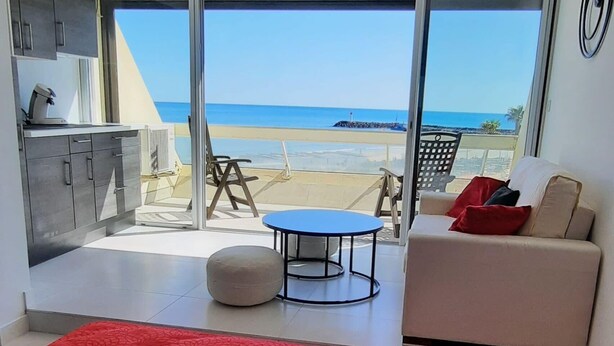 Un salon moderne doté d’une grande porte-fenêtre coulissante donnant sur un balcon avec vue sur la plage.