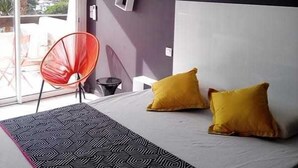 A bedroom with a bed, two yellow pillows, a red chair, and a patterned rug. - Naturiste Cap d'Agde Port Nature 650 (Agde)