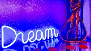 Une enseigne au néon avec le mot « Rêve » et une sculpture représentant un couple.