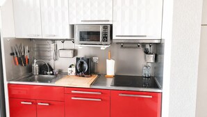 Eine moderne Küche mit Edelstahlgeräten, roten Schränken und einer Mikrowelle über der Spüle.