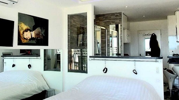 A modern bedroom with a large bed, a built-in desk, and a view of the kitchen. - Naturiste Cap d'Agde Héliopolis F 72 (Agde)