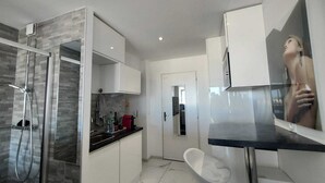 A modern bathroom with a glass shower enclosure, a white sink, and a large mirror. - Naturiste Cap d'Agde Héliopolis F 72 (Agde)