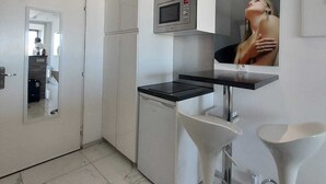 A modern kitchen with white cabinetry, a built-in microwave, a black countertop, and a stainless steel sink. - Naturiste Cap d'Agde Héliopolis F 72 (Agde)