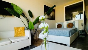 A modern bedroom with a bed, a white sofa, and a coffee table with a vase of flowers.