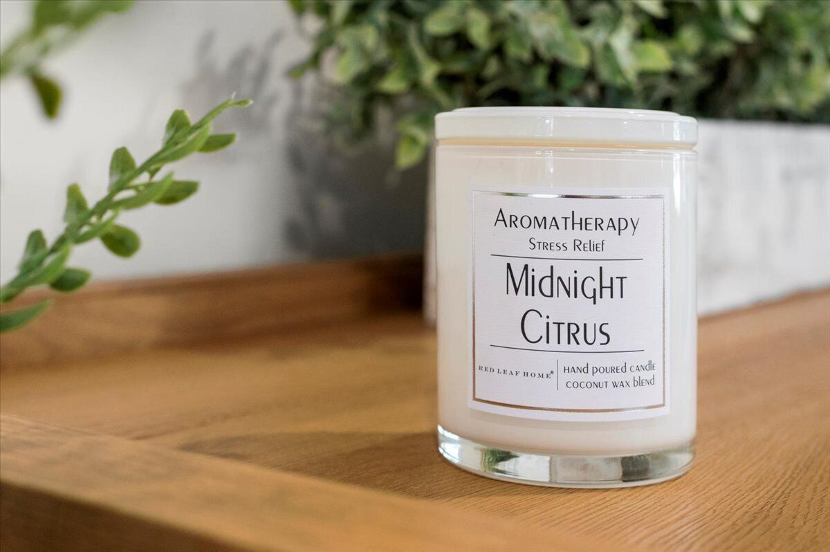 A hand-poured candle labeled "Midnight Citrus" with a label indicating it is a red leaf home blend.