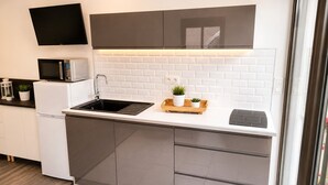 Une cuisine moderne équipée d’un four à micro-ondes encastré, d’un évier et d’un plateau en bois agrémenté de plantes.