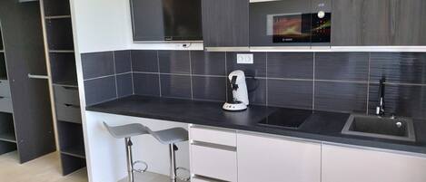 Una cocina moderna con encimera negra, una cafetera Bosch y un horno empotrado.
