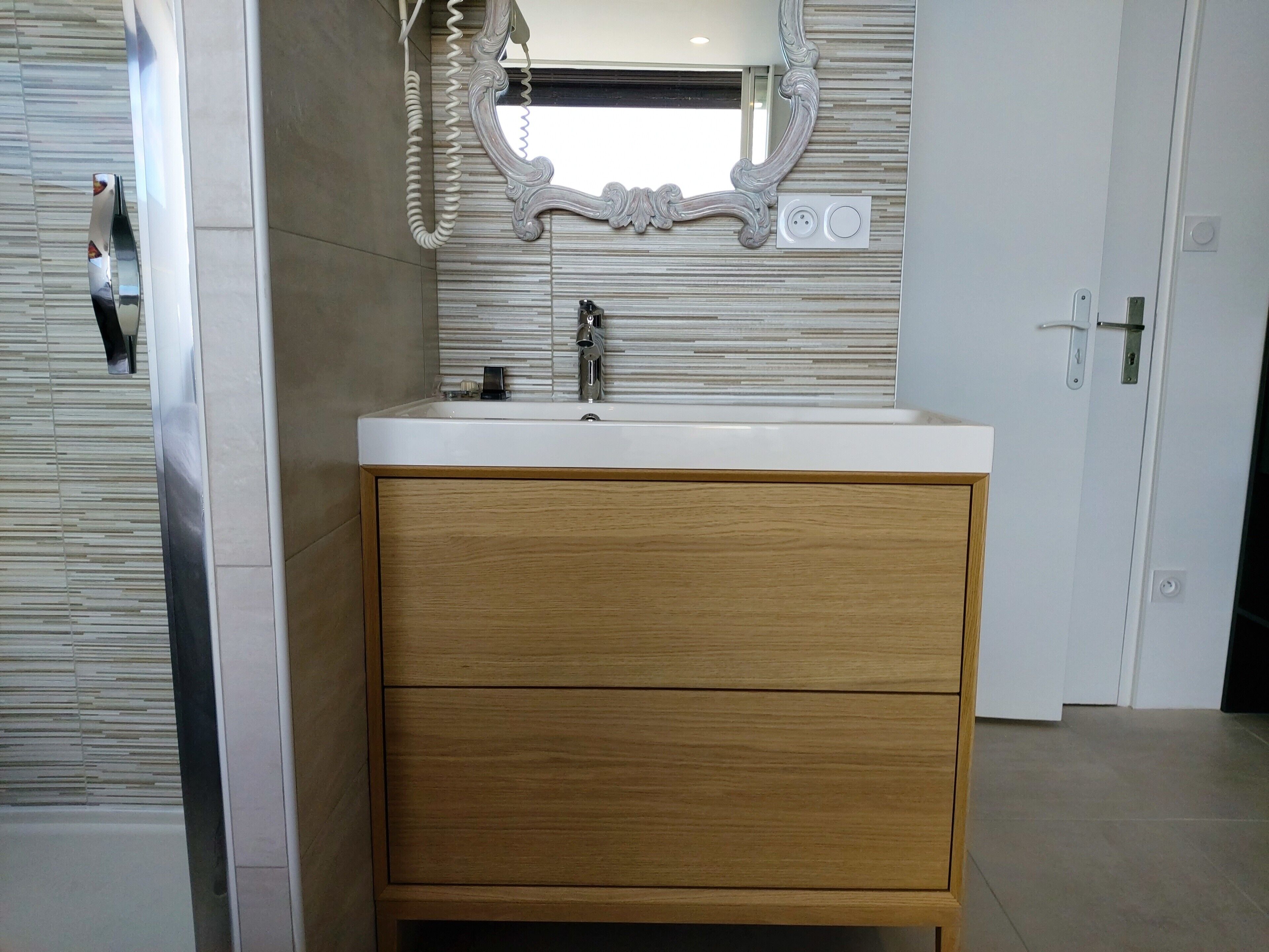 Une salle de bain avec un meuble-lavabo en bois, un miroir doté d’un cadre orné et un lavabo moderne.