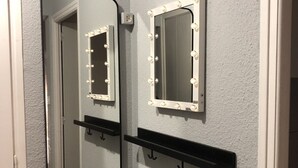 A bathroom with two mirrors, one with lights and a black shelf. - Naturiste Cap d'Agde Héliopolis F 31 (Agde)