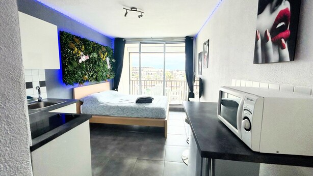Un appartement moderne doté d’une cuisine, d’un lit et d’un balcon.