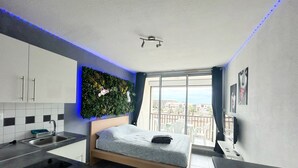 Une chambre moderne comprenant un lit, une petite kitchenette, un balcon avec vue et un mur décoratif.