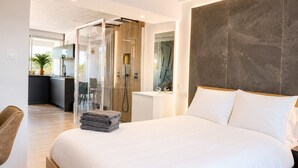 Un dormitorio moderno con una cama grande, una zona de ducha y vistas a la cocina.