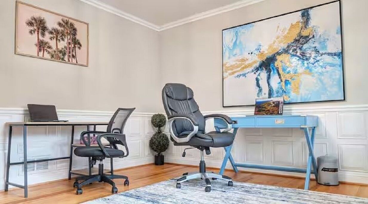 Ein Home-Office mit zwei Bürostühlen, einem Schreibtisch, einem Laptop und einem großen abstrakten Gemälde an der Wand.