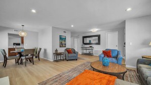 A modern living room with a dining area, a TV mounted on the wall, and a large window. - Spacious Home with Gazebo, Lounge Near Lake Balboa (Los Angeles)