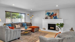 A modern living room with a fireplace, a sofa set, a coffee table, and a large abstract painting. - Spacious Home with Gazebo, Lounge Near Lake Balboa (Los Angeles)