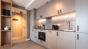 A modern kitchen with white cabinets, a built-in oven, and a coffee maker. - Spacious Apartment in Den Haag With View (The Hague)