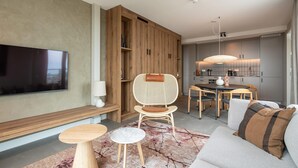 A modern living room with a flat-screen TV, wooden furniture, a dining area, and a kitchen in the background. - Spacious Apartment in Den Haag With View (The Hague)