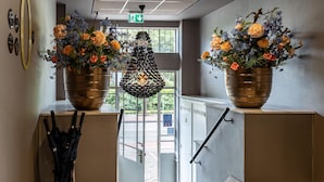 A hallway with two large flower pots on a landing, a black umbrella stand, and a door leading outside. - Cozy and Budget-friendly Studio Apartment (The Hague)