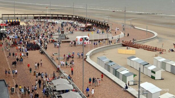 A crowded beach with a curved promenade, a statue, and beach huts. - Seaview Apartment in De Haan for two (De Haan)