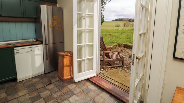 Une cuisine équipée d’un réfrigérateur, d’un lave-vaisselle et d’un tabouret en bois.