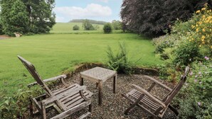 Un jardin avec un banc et une table en bois, entouré de galets et de verdure.