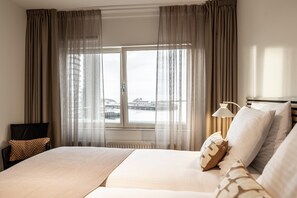 Une chambre d’hôtel avec un grand lit, une chaise, une lampe et une vue sur le bord de l’eau.