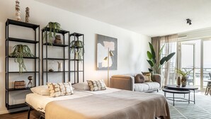 Un dormitorio moderno con una cama grande, un sofá y un balcón con plantas.
