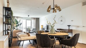 Un salón moderno con una mesa de comedor redonda, sillas tapizadas oscuras y una lámpara colgante.