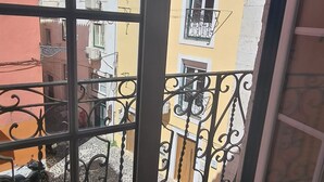 A view from a balcony with metal railings, overlooking a building with multiple balconies and air conditioning units. - Castle Fado River Alfama Flat (Lisbon)
