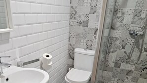 A bathroom with a white sink, toilet, and shower. - HOSTAL MARIQUITO (Fisterra)