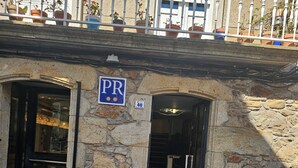 A stone building with a sign indicating a parking area (PR) and a number 40. - HOSTAL MARIQUITO (Fisterra)