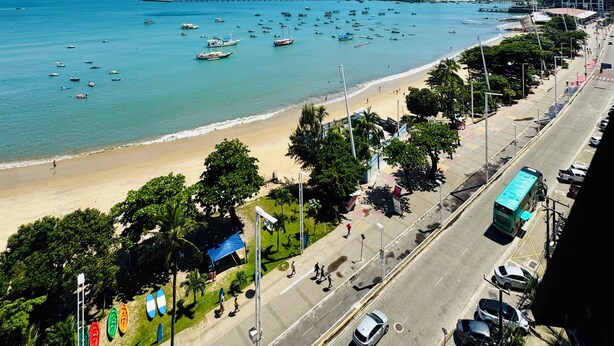 A coastal cityscape with a beach, boats, and a road lined with trees and buildings. - DM Ceara Golden Fortaleza - Beach (Meireles Fortaleza)