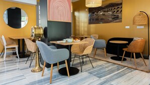 Un comedor moderno con una mesa redonda, sillas de mimbre y un sofá negro.