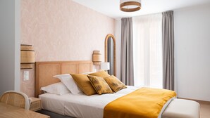 Quarto de hotel bem arrumado, com cama, mesas de cabeceira, painel de madeira e uma janela grande com cortinas.