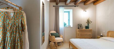 Un dormitorio con cama, una silla, cómoda y armario.