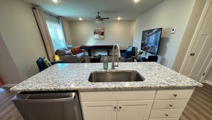 Una cocina moderna con encimeras de granito, lavavajillas de acero inoxidable y armarios blancos.