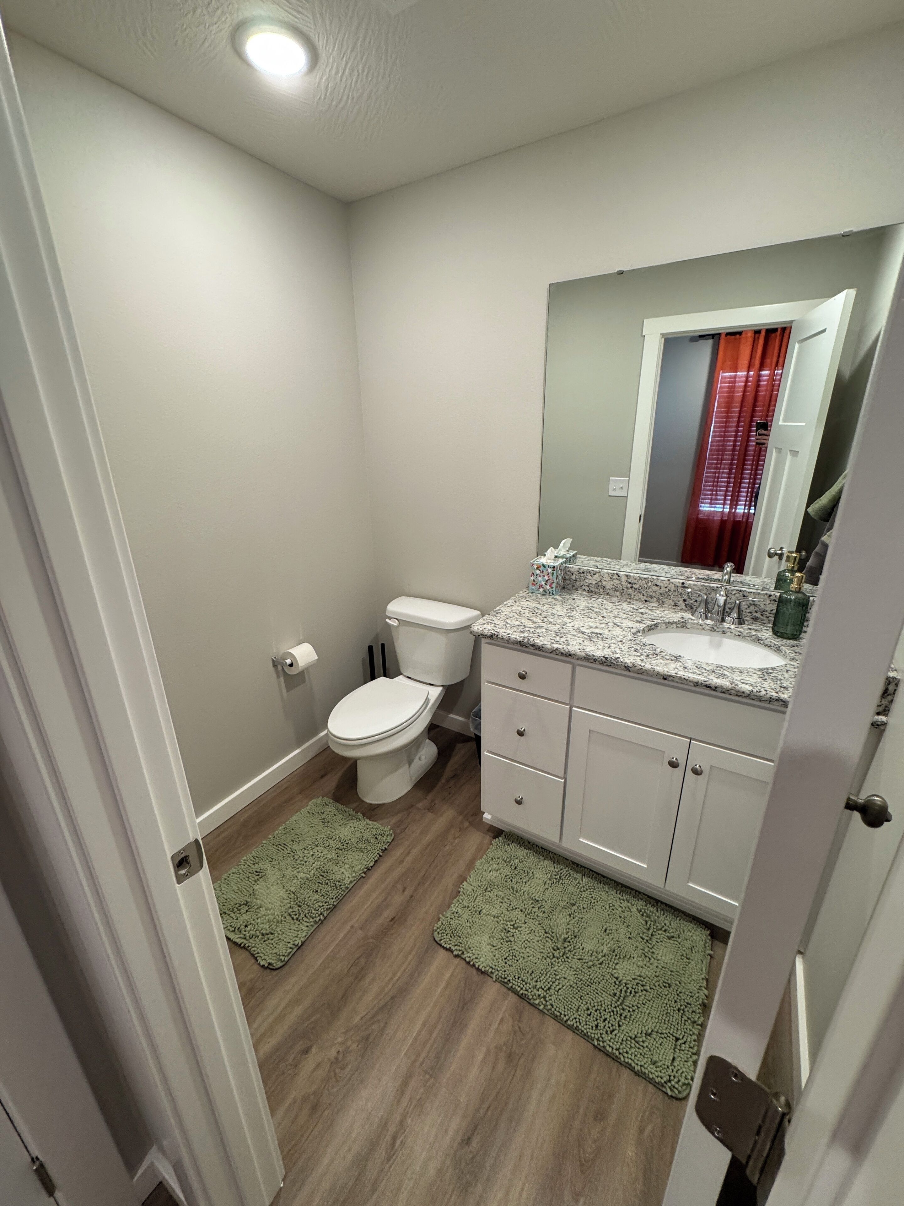A compact bathroom with a toilet, sink, and mirror.